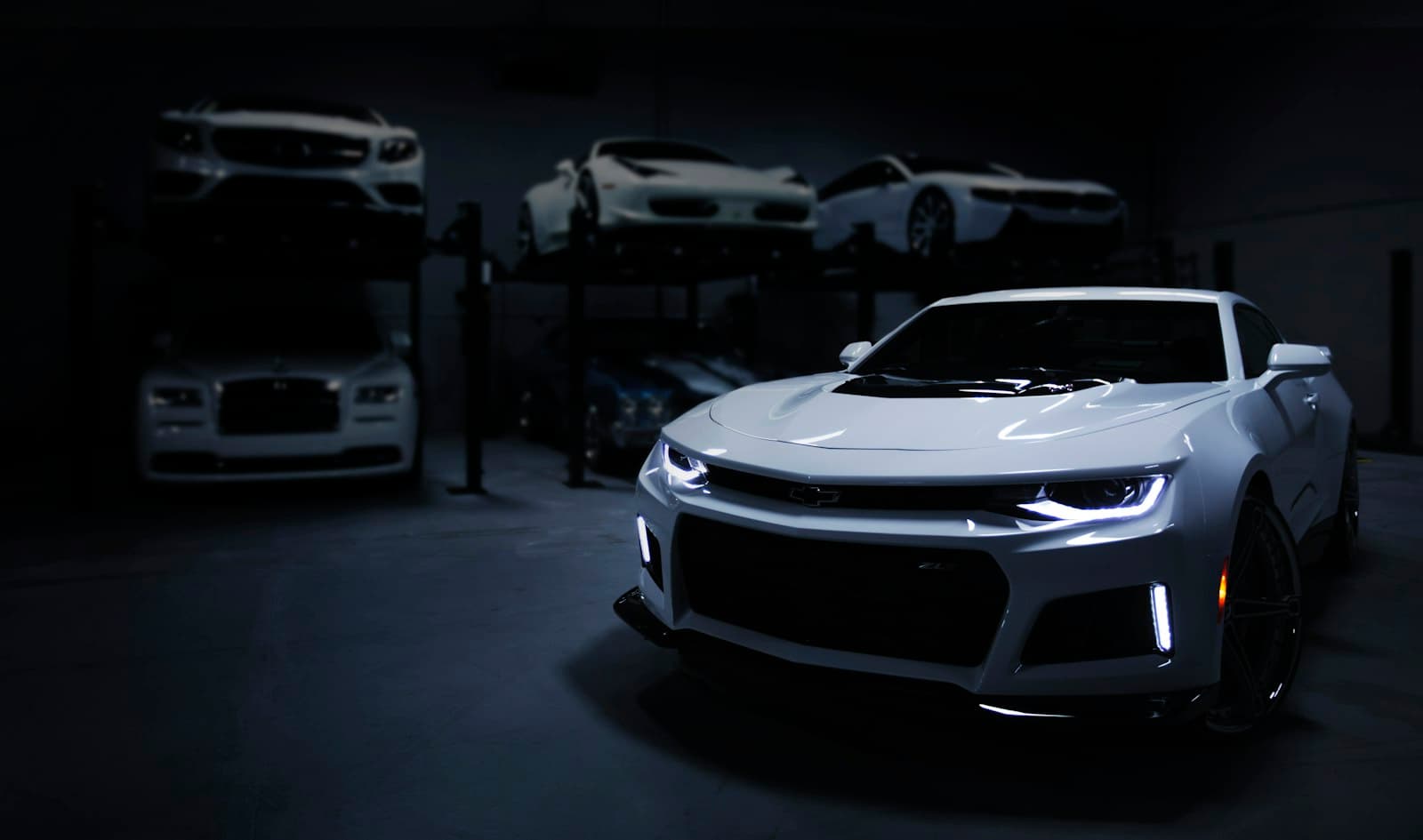 A sports car in a dimly lit showroom with other vehicles behind it