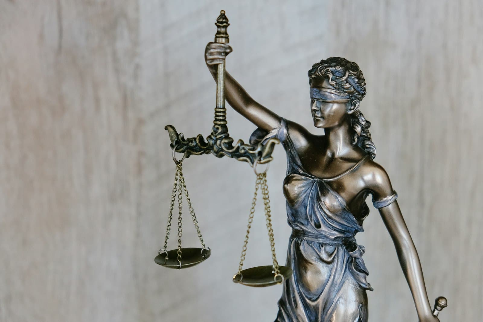 A bronze statue of Lady Justice holding balanced scales