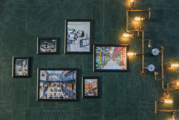 Industrial style wall art with vintage pipe lighting on a green textured wall adds a unique touch.